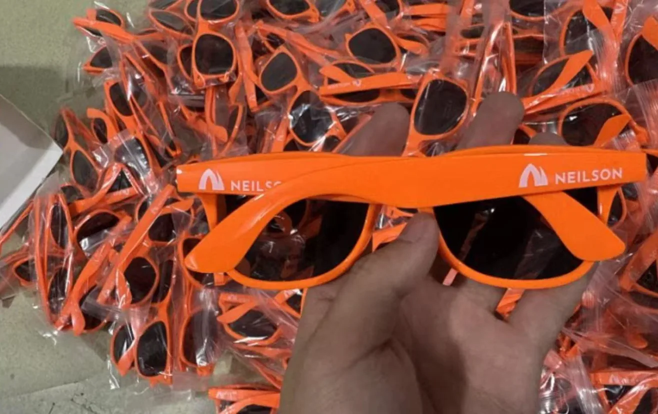 Custom private label sunglasses with client logo printed on temple arms, individually polybagged orange frames in bulk production